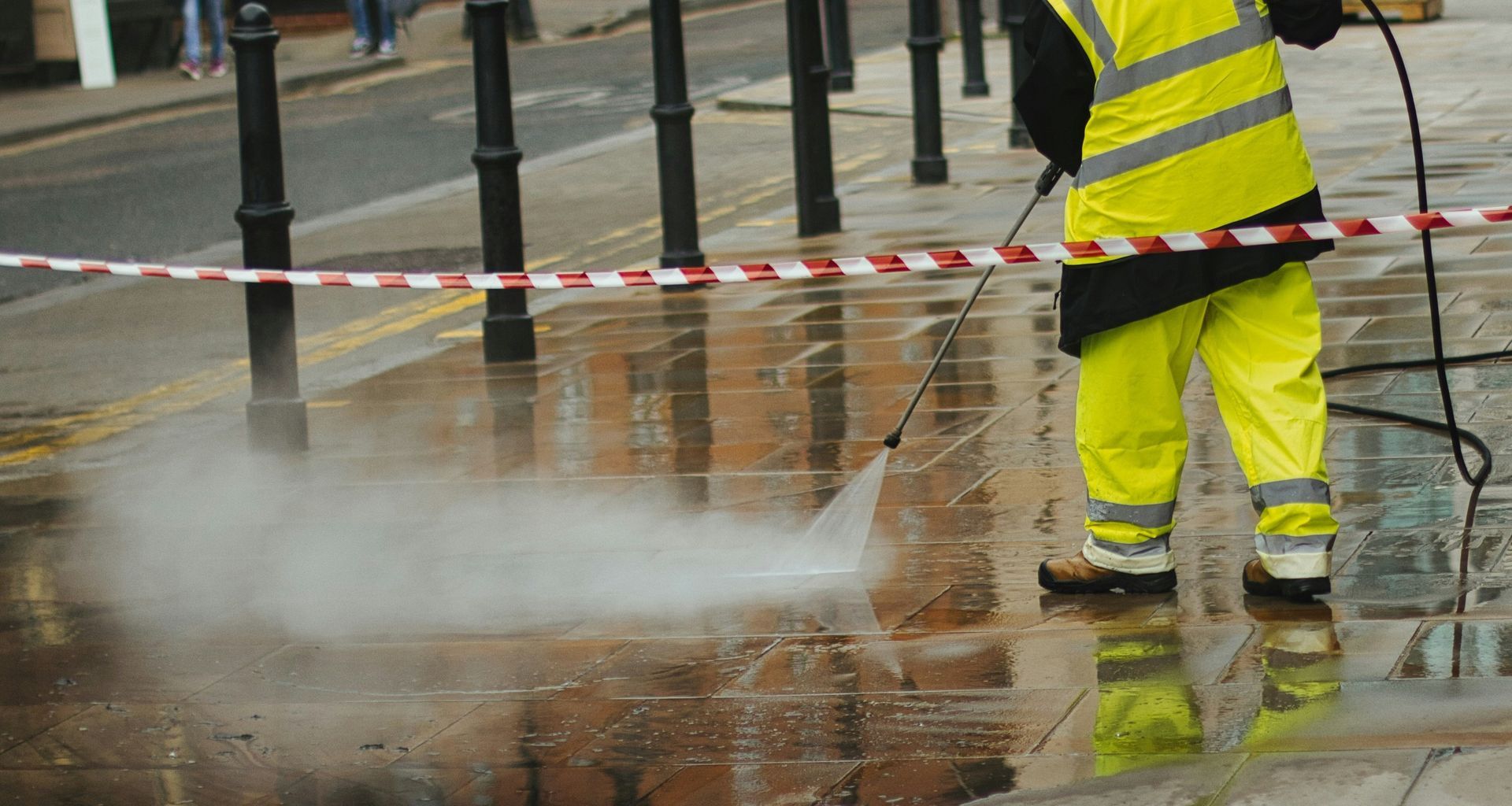 a man in a yellow jacket is using a pressure washer