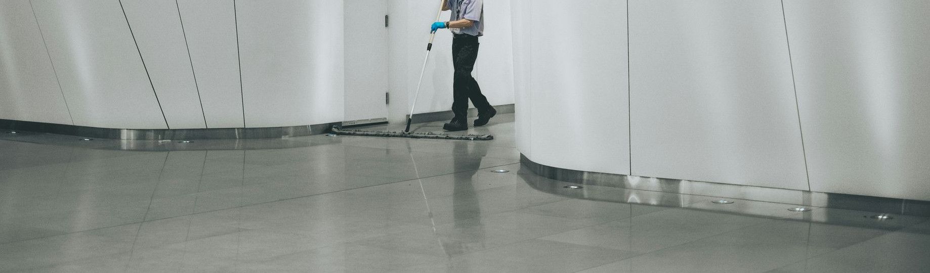 man cleaning on floor beside white wall