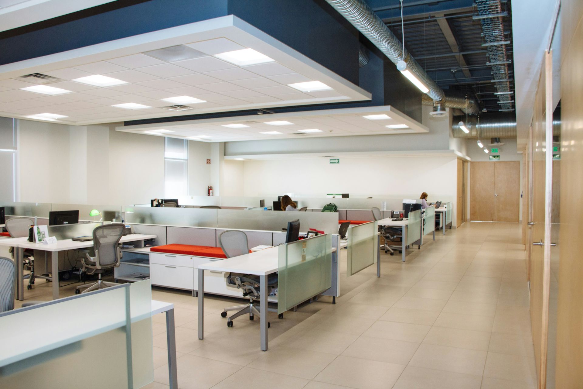 An open plan office with rows of white desks and frosted glass partitions